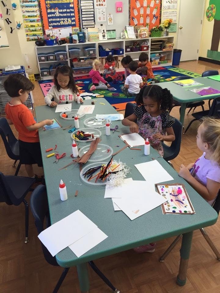 Children doing crafts at a table in a classroom