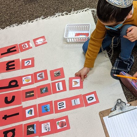 Child on floor matching cards with letters and images