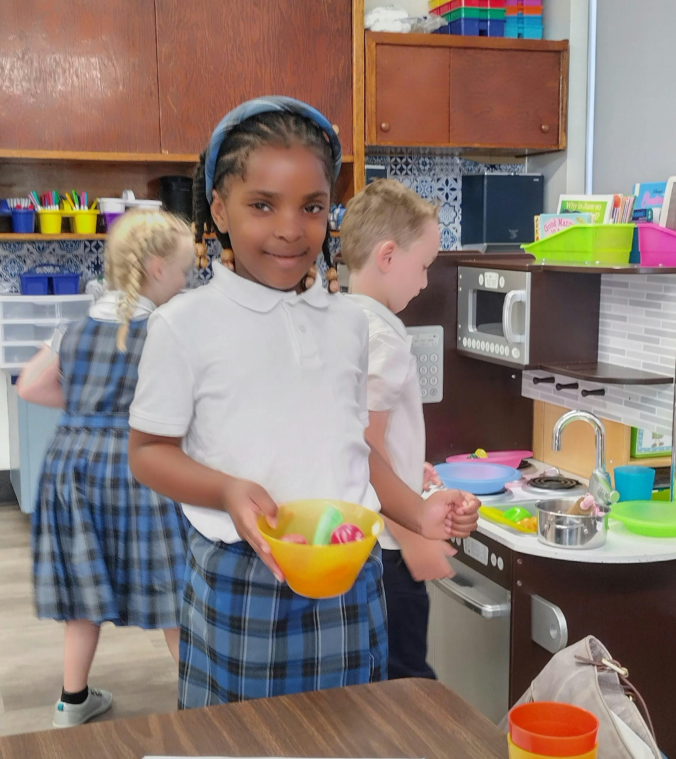 Child holding a bowl of play food in a classroom