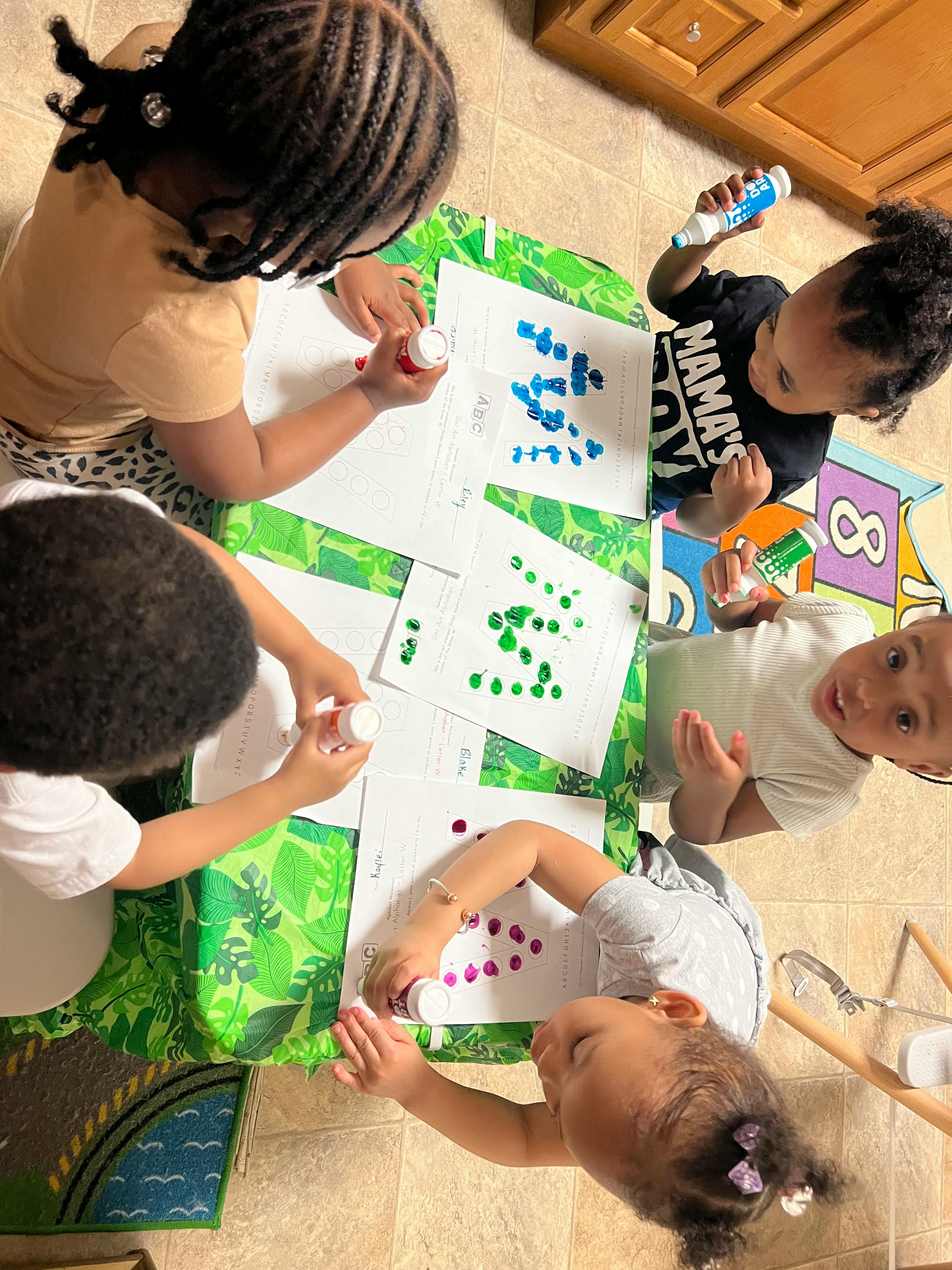 Four children doing dot painting at a table