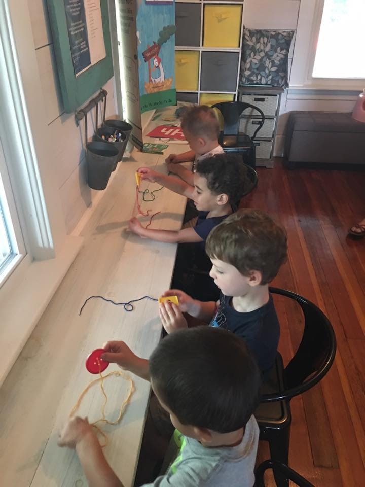 Children playing with string and beads at a counter