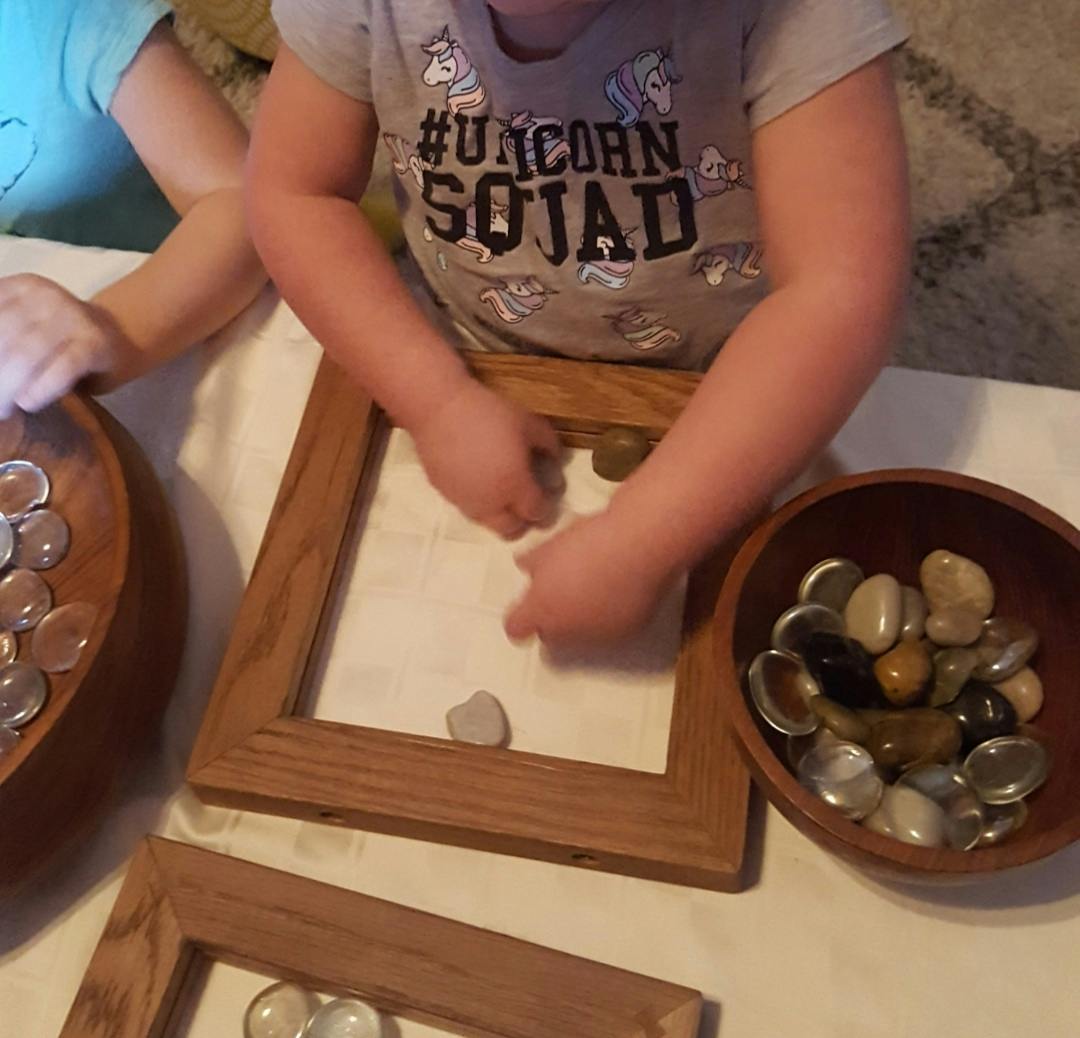 Child playing with stones and wooden frames