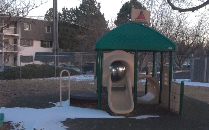 A small playground structure with a slide and a KinderCare sign
