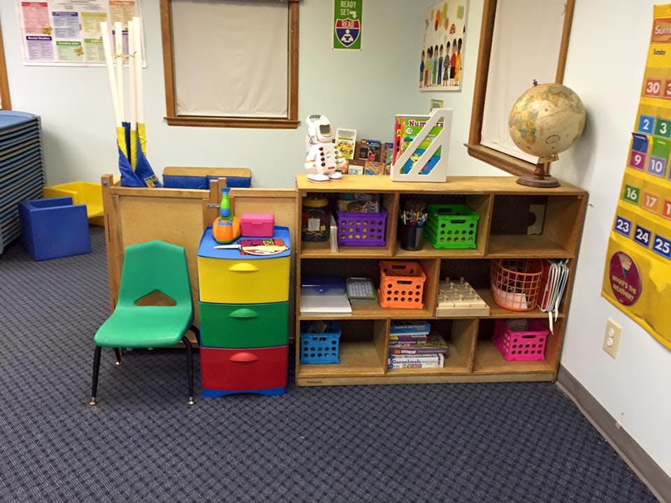 Green chair next to colorful drawers and a wooden shelf with shelves