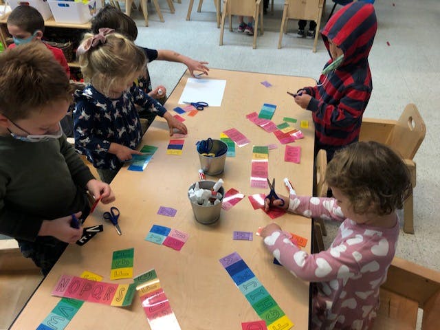 Children cutting colorful paper strips at a table