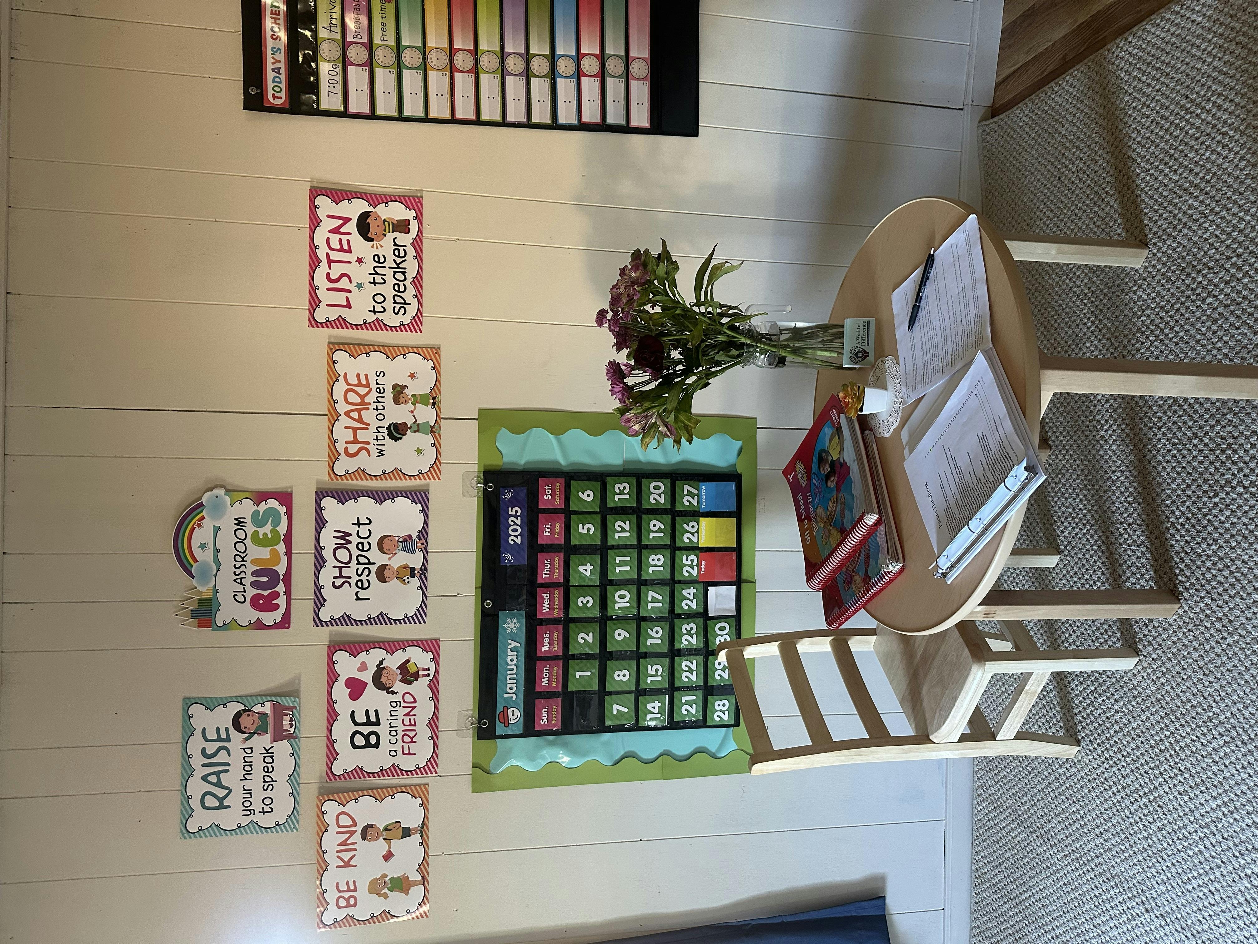 Classroom with a small table and chair, calendar, and rules posters on the wall