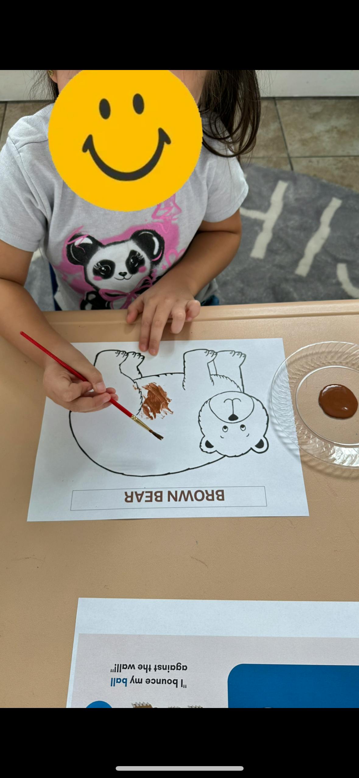 Child painting a brown bear outline on paper