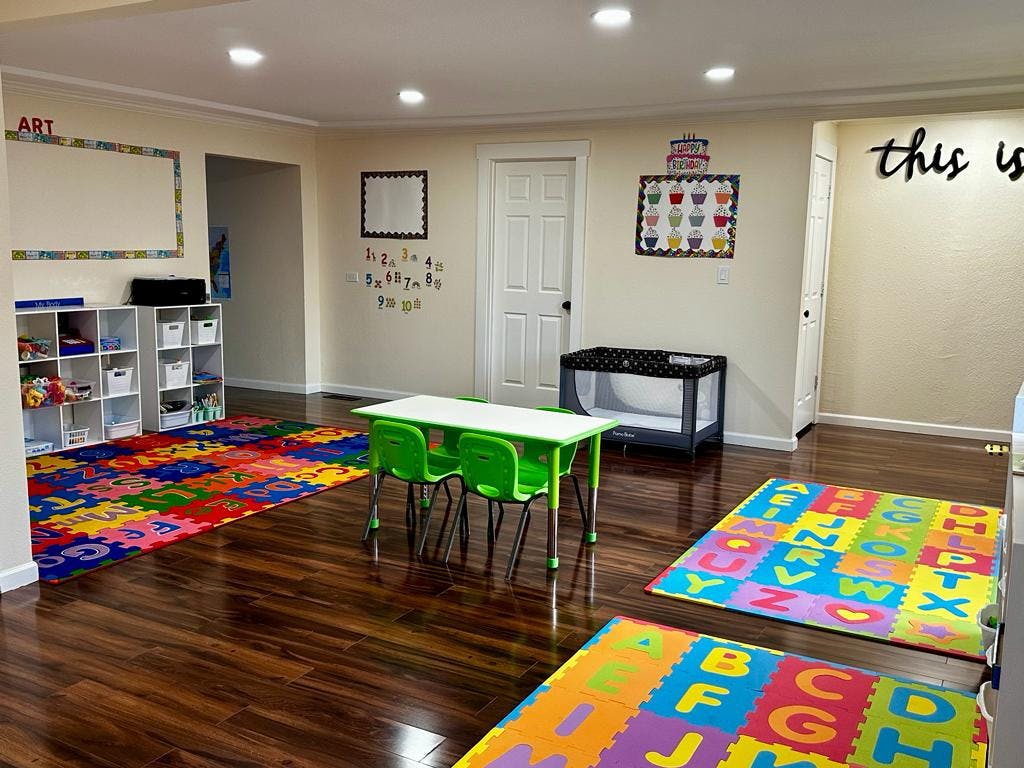 Playroom with small table and chairs, colorful alphabet mats, and storage shelves