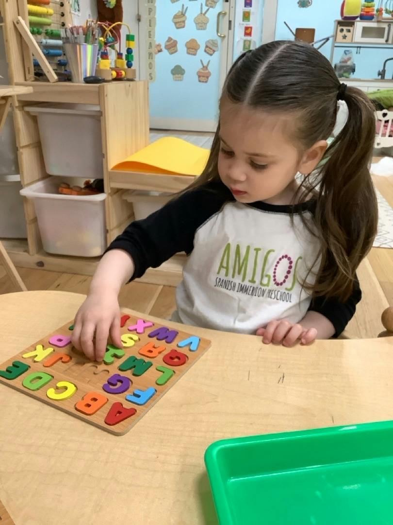 Child placing a letter piece into an alphabet puzzle