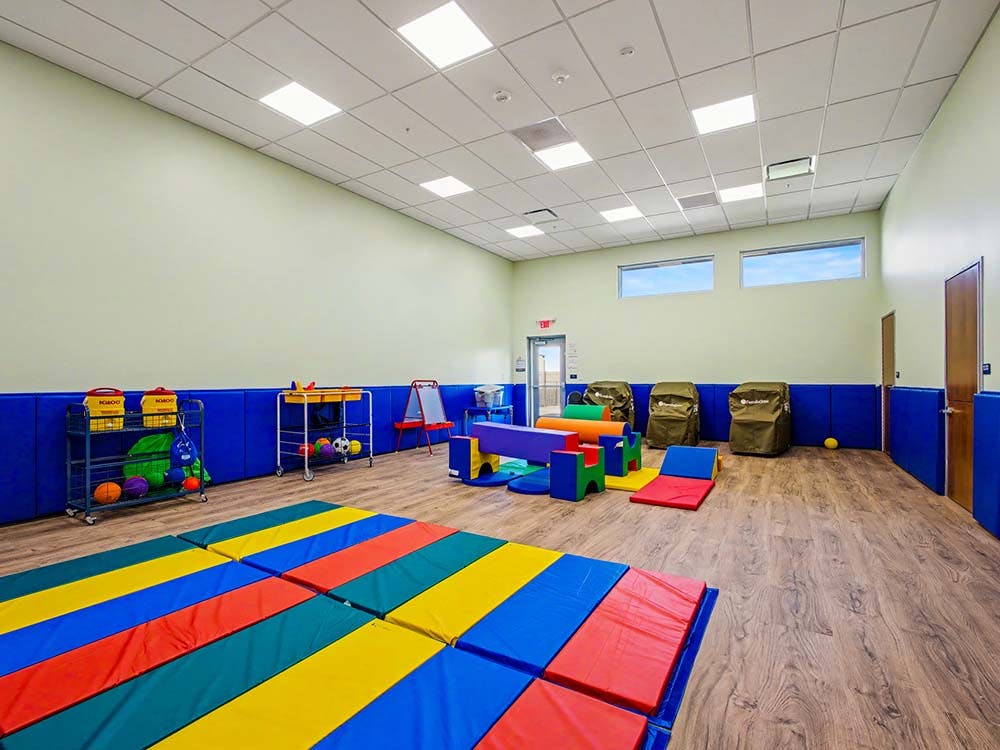 Children's play room with colorful floor mats, soft play structures, and toy carts