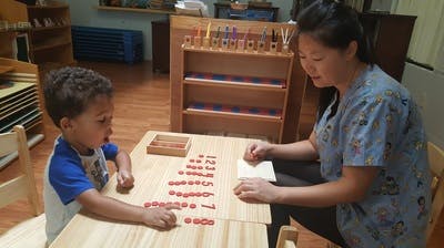 Adult and child at table with number blocks