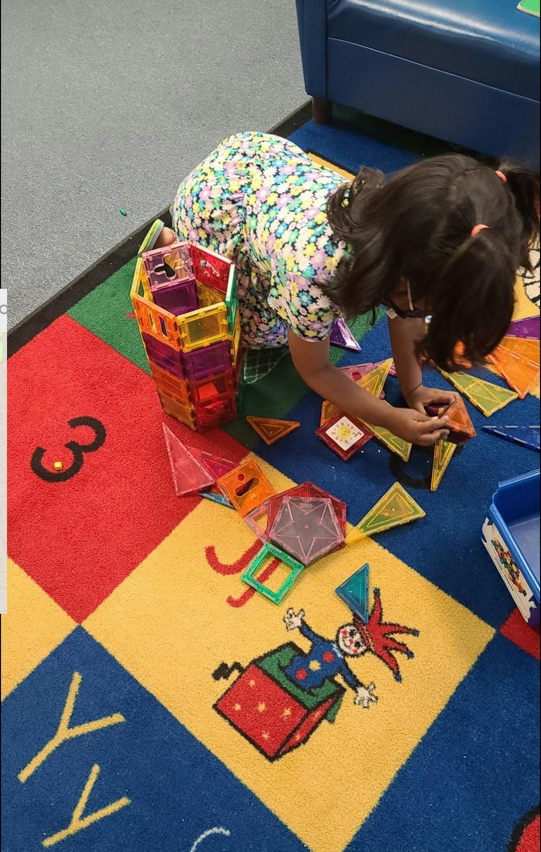 Child playing with colorful magnetic tiles on a patterned rug