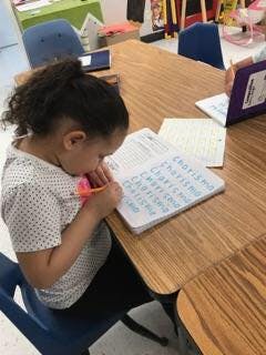 Child writing on paper at a table