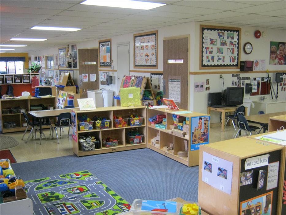 An empty early childhood classroom with toys, tables, and learning displays