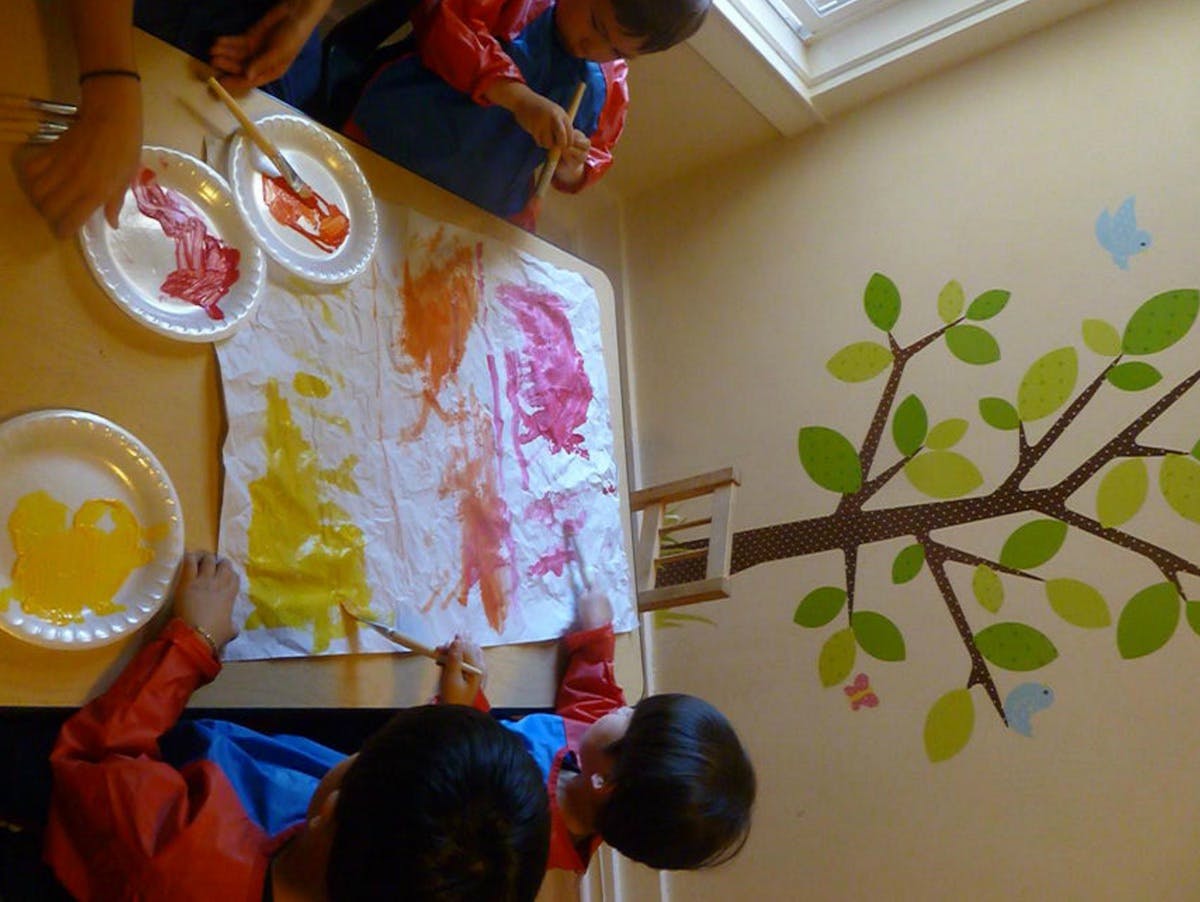 Children painting on a large white sheet with colorful paints