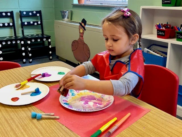 Child painting on a paper plate at a table