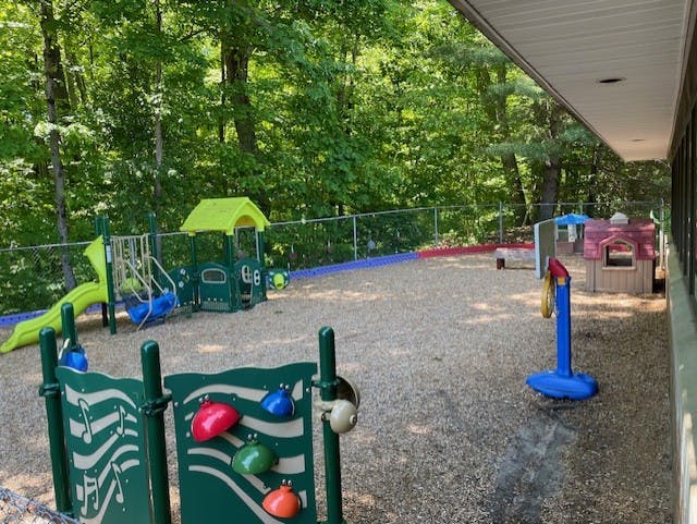 Playground with green and yellow slide, swing set, and playhouse