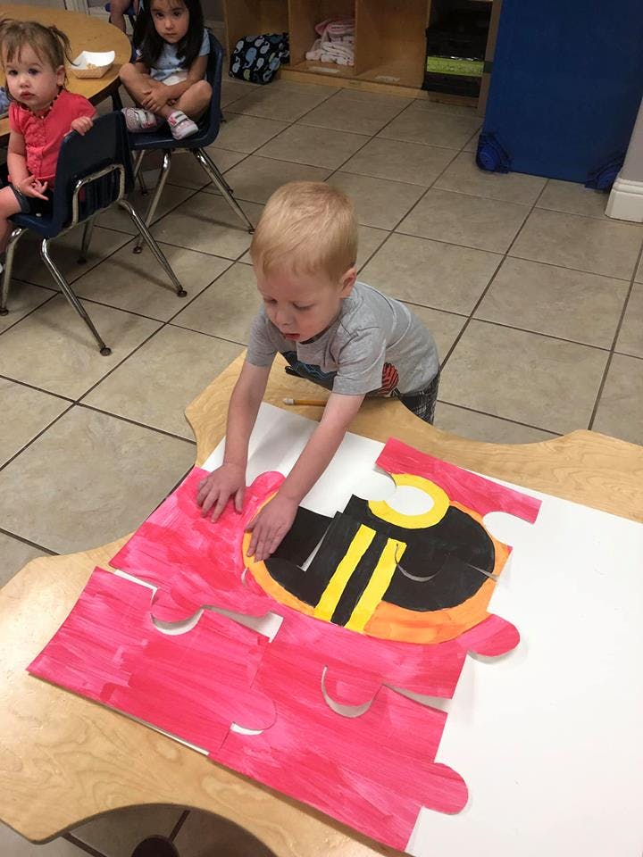 Child playing with a large puzzle on a table