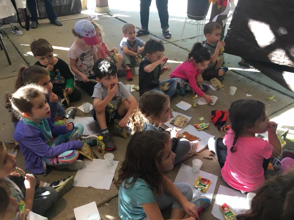 Group of children sitting on the ground with papers and small items