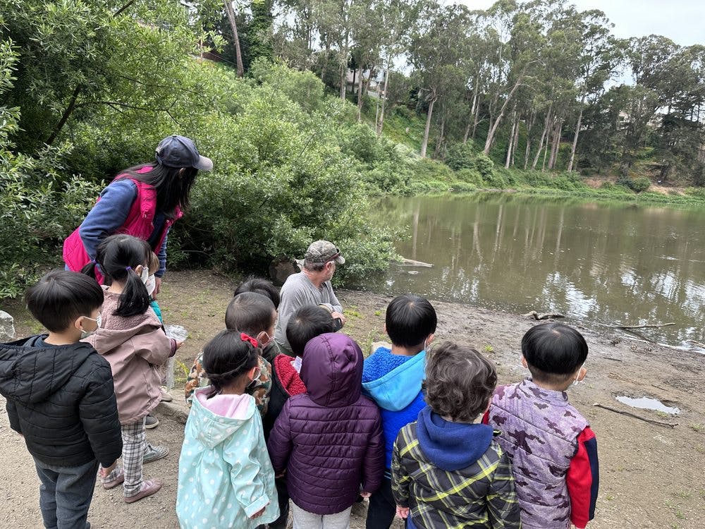 Adults and children gathered by a body of water