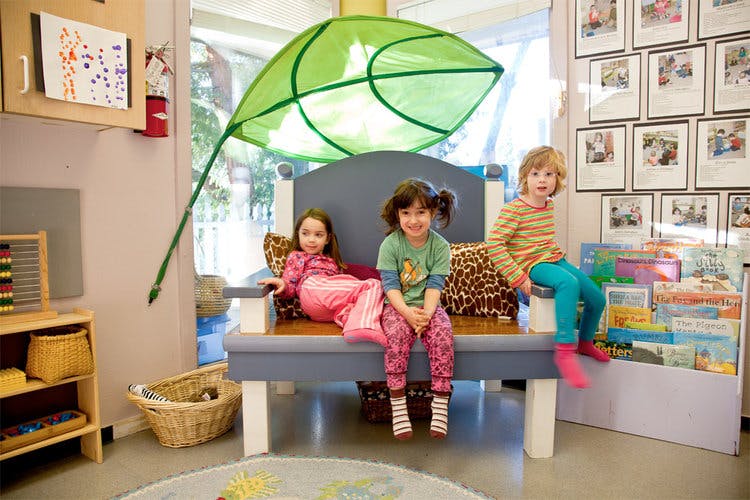 Three children sitting on a bench in a classroom