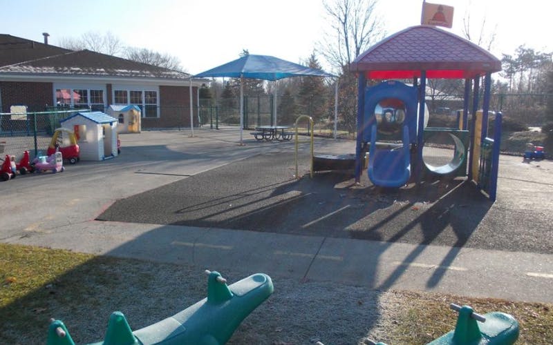 Empty children's playground with a slide, tunnels, toy cars, and small playhouses