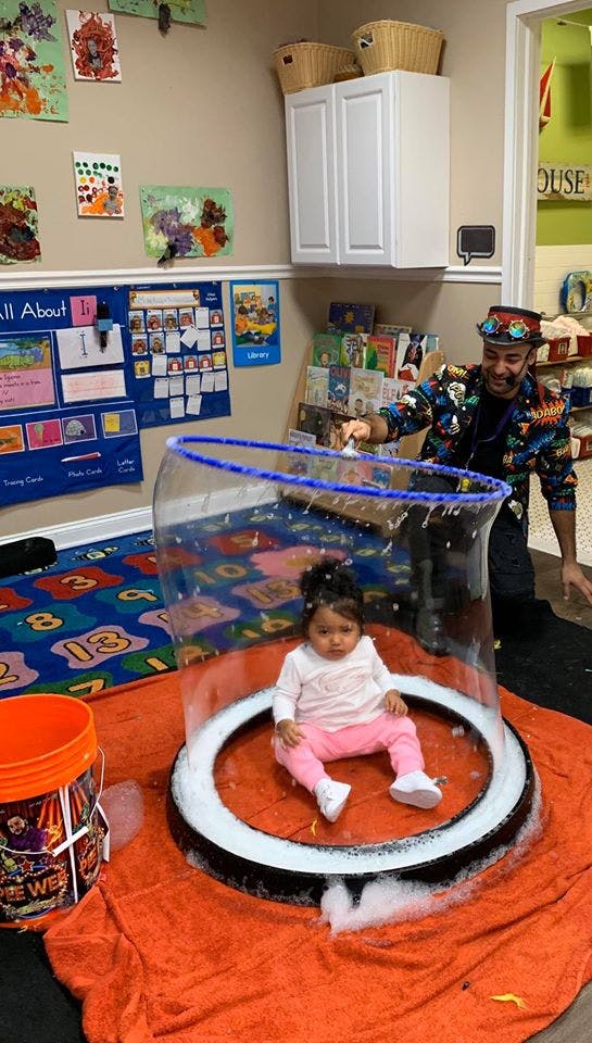 Person creating a large bubble around a child sitting on a platform