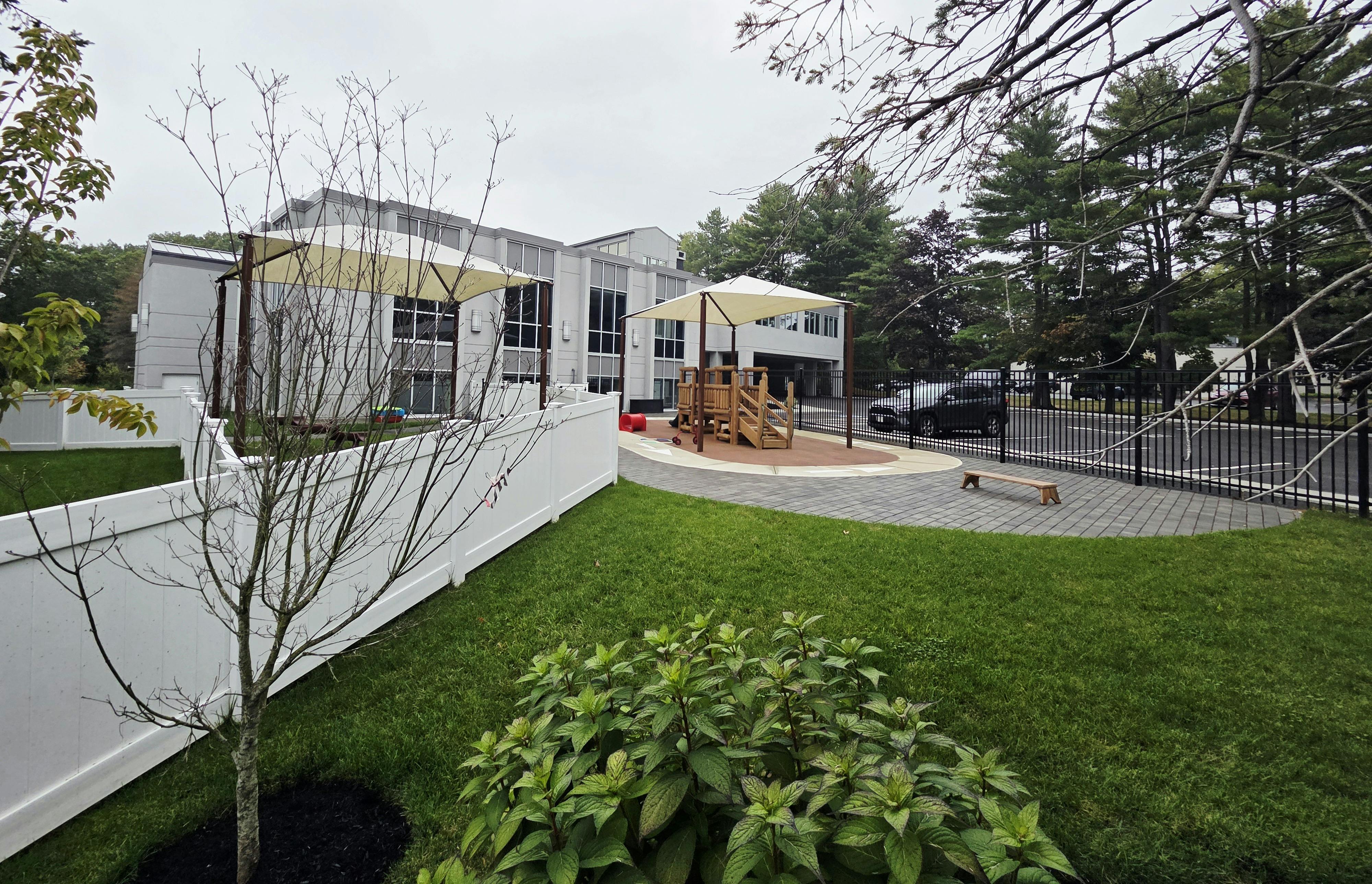 A modern building with large windows and a playground with shade structures