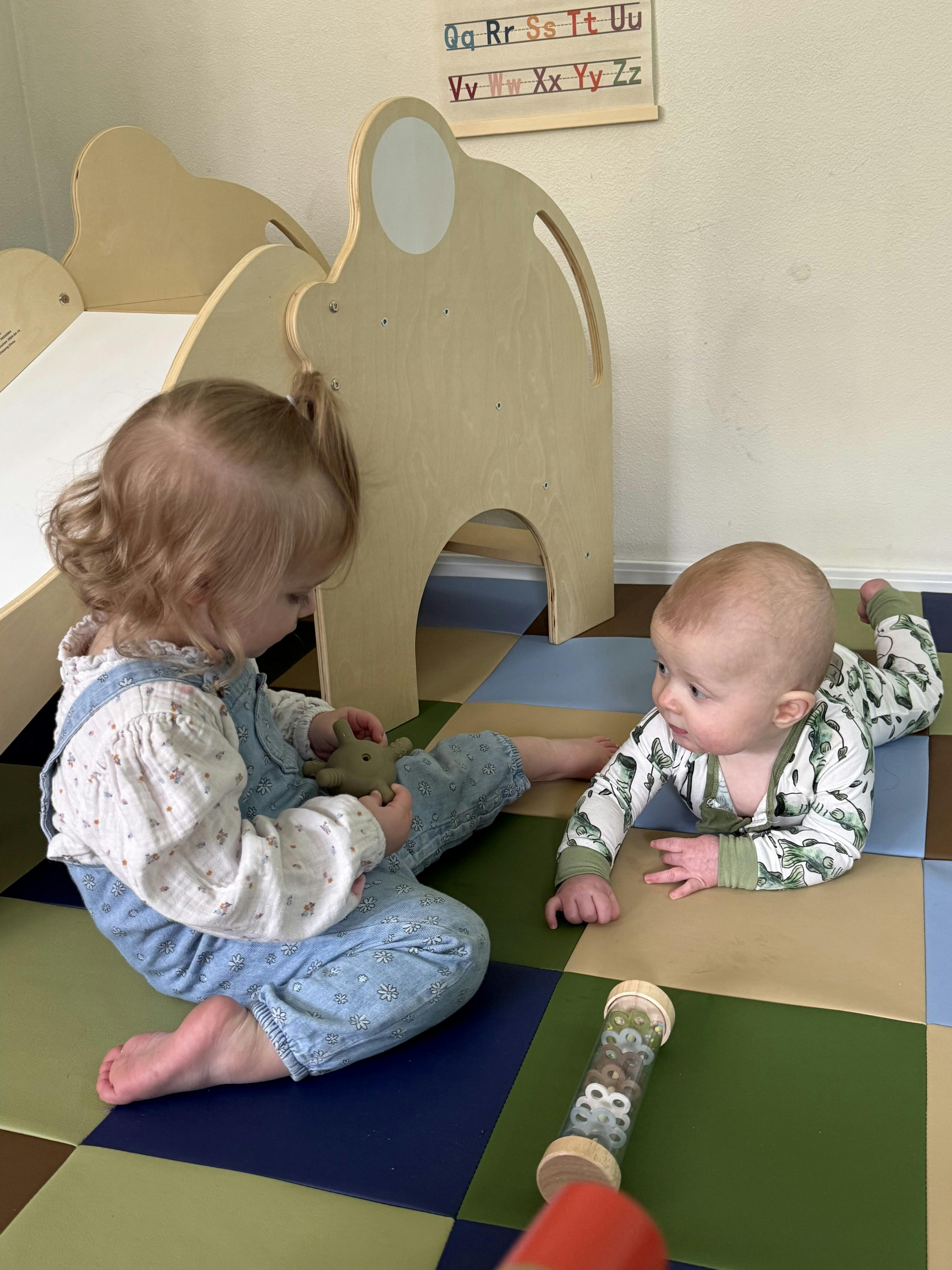Child sitting on floor holding toy, baby crawling on floor