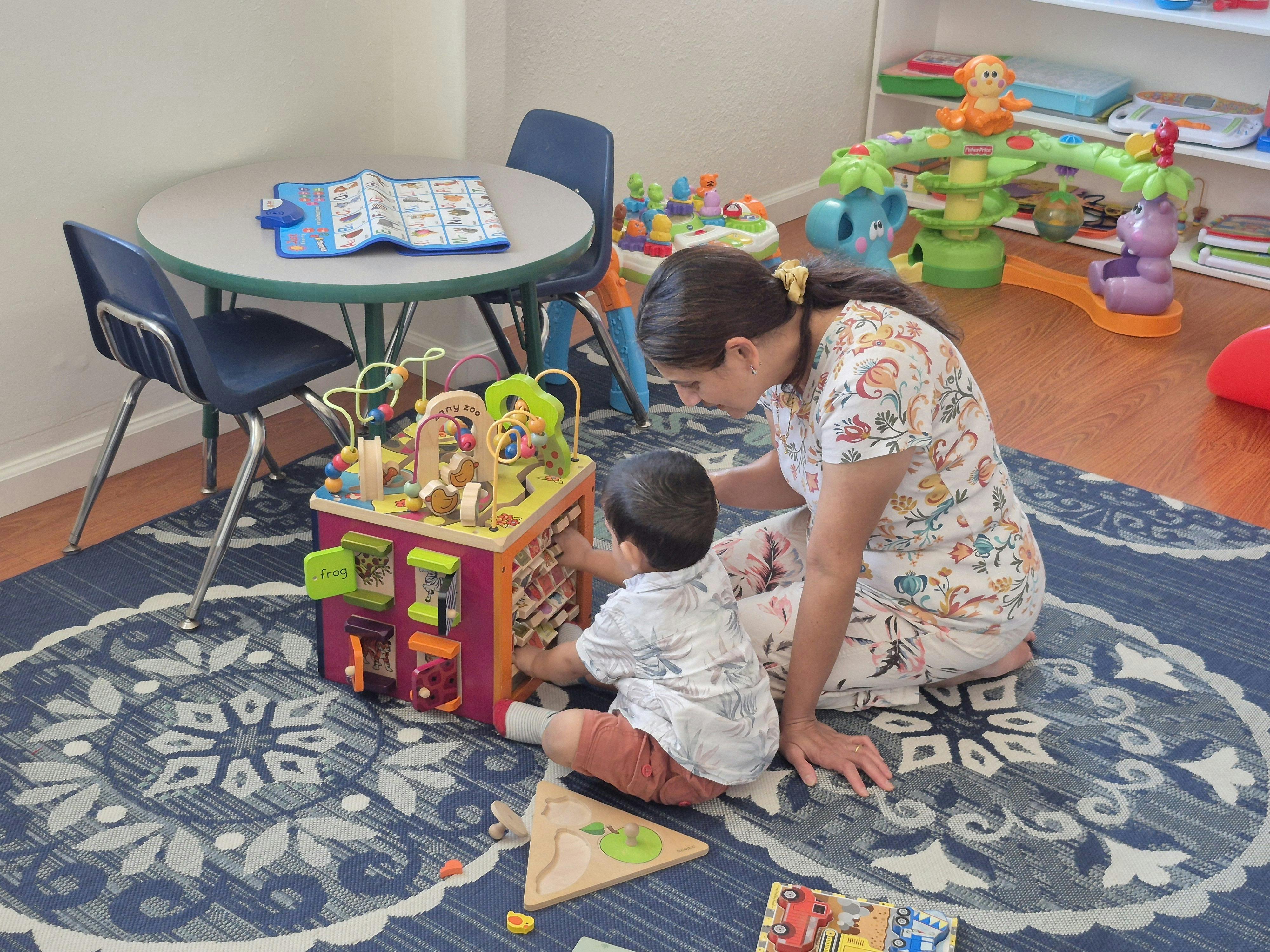 Person and child playing with an activity cube on a rug