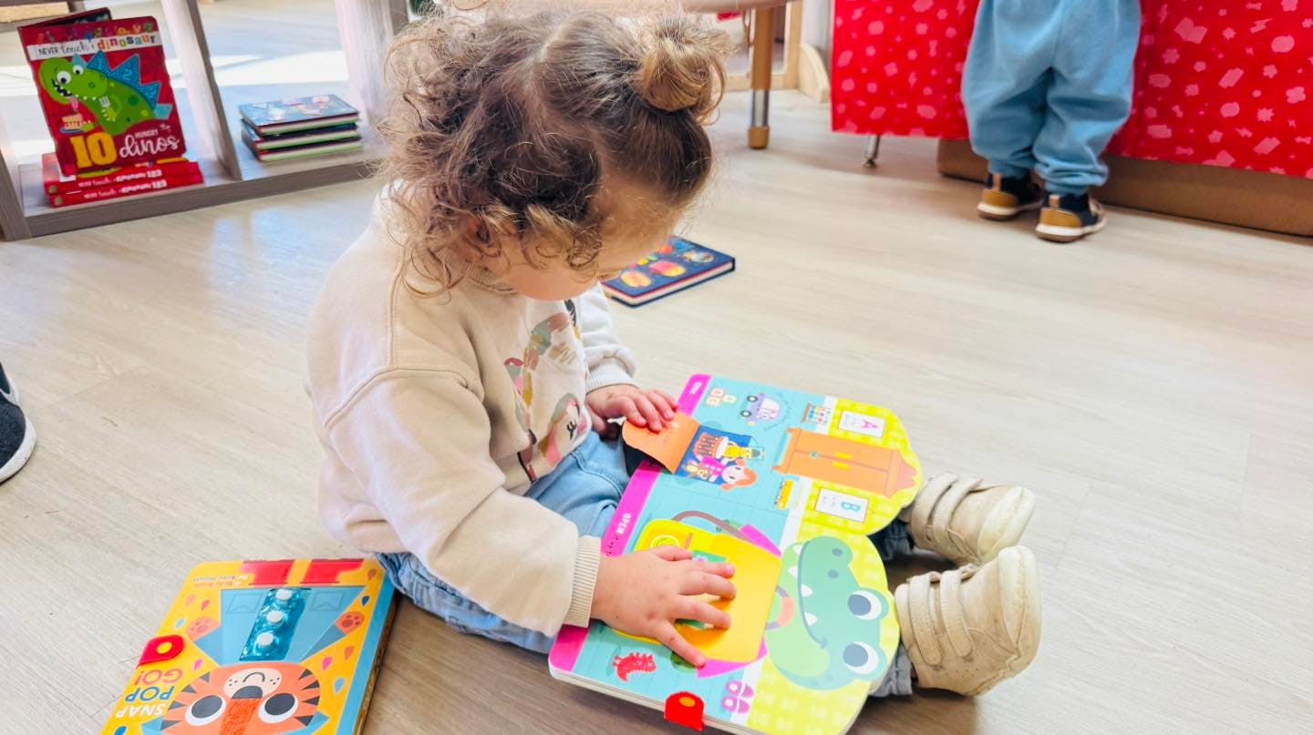 Child sitting on the floor reading a colorful book