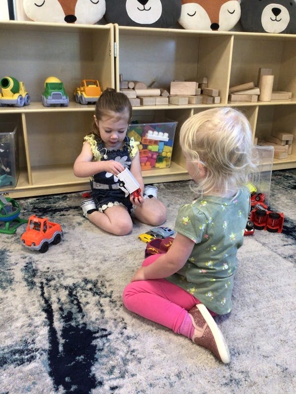 Two children playing with toys on a rug