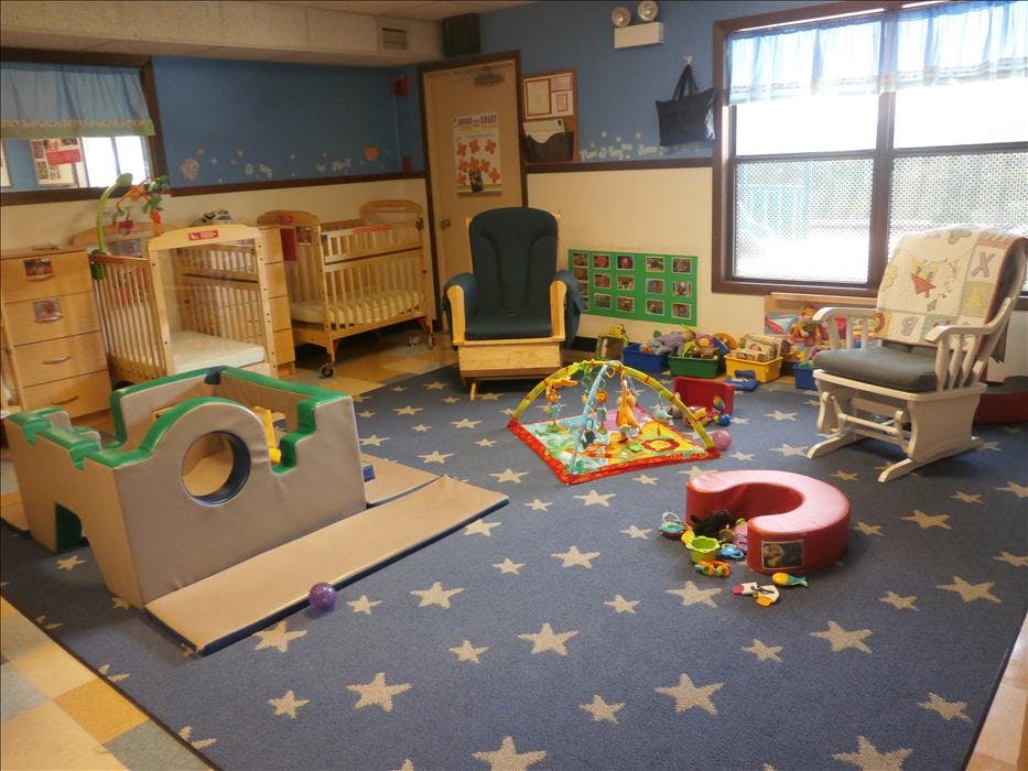 A colorful playroom with two cribs, soft play equipment, and scattered toys