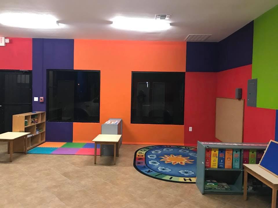 Colorful classroom with small tables, chairs, and a round rug