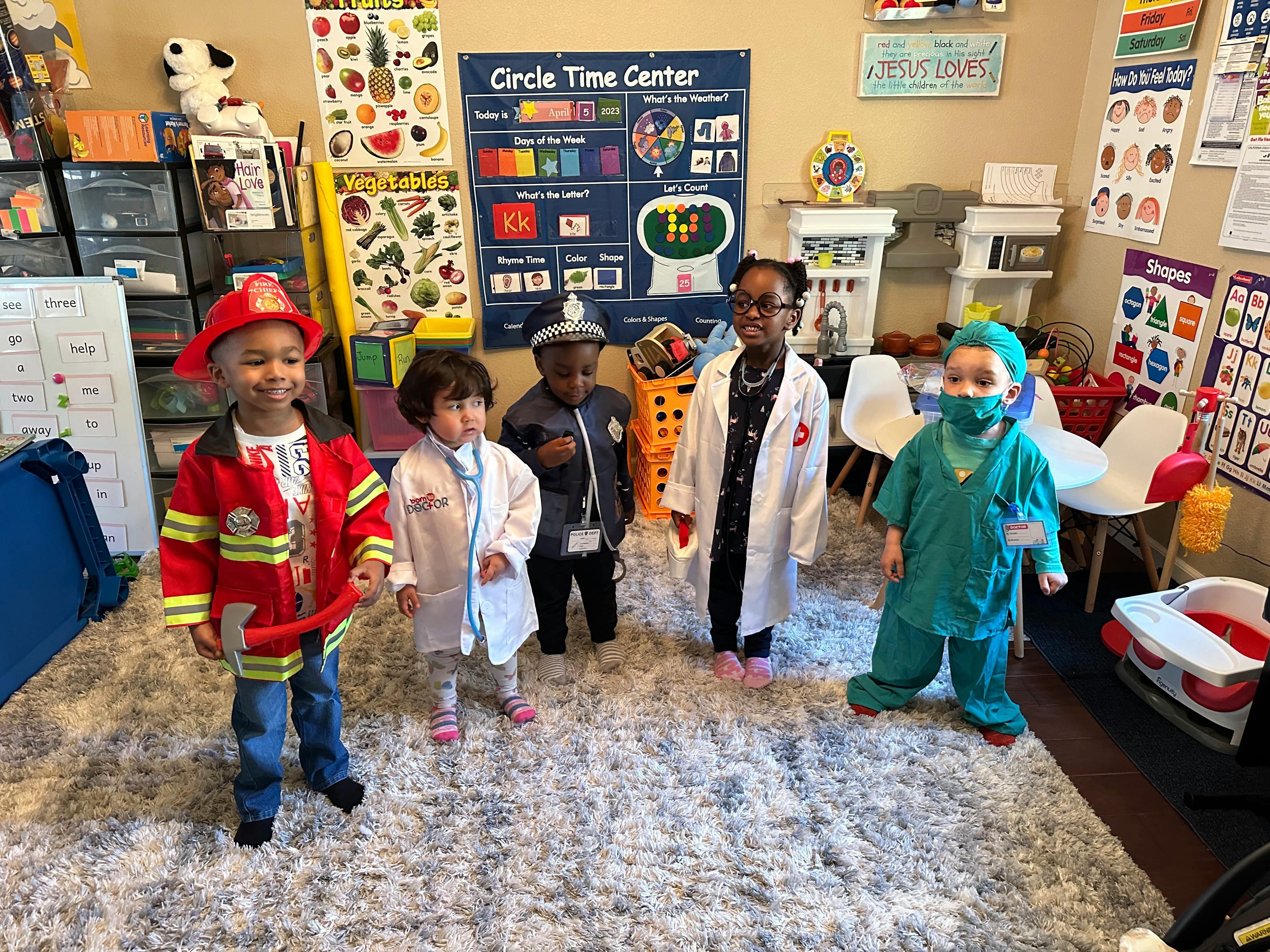 Five children in various career costumes in a classroom