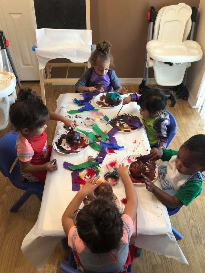 Children sitting around a table doing an art activity with paint and paper