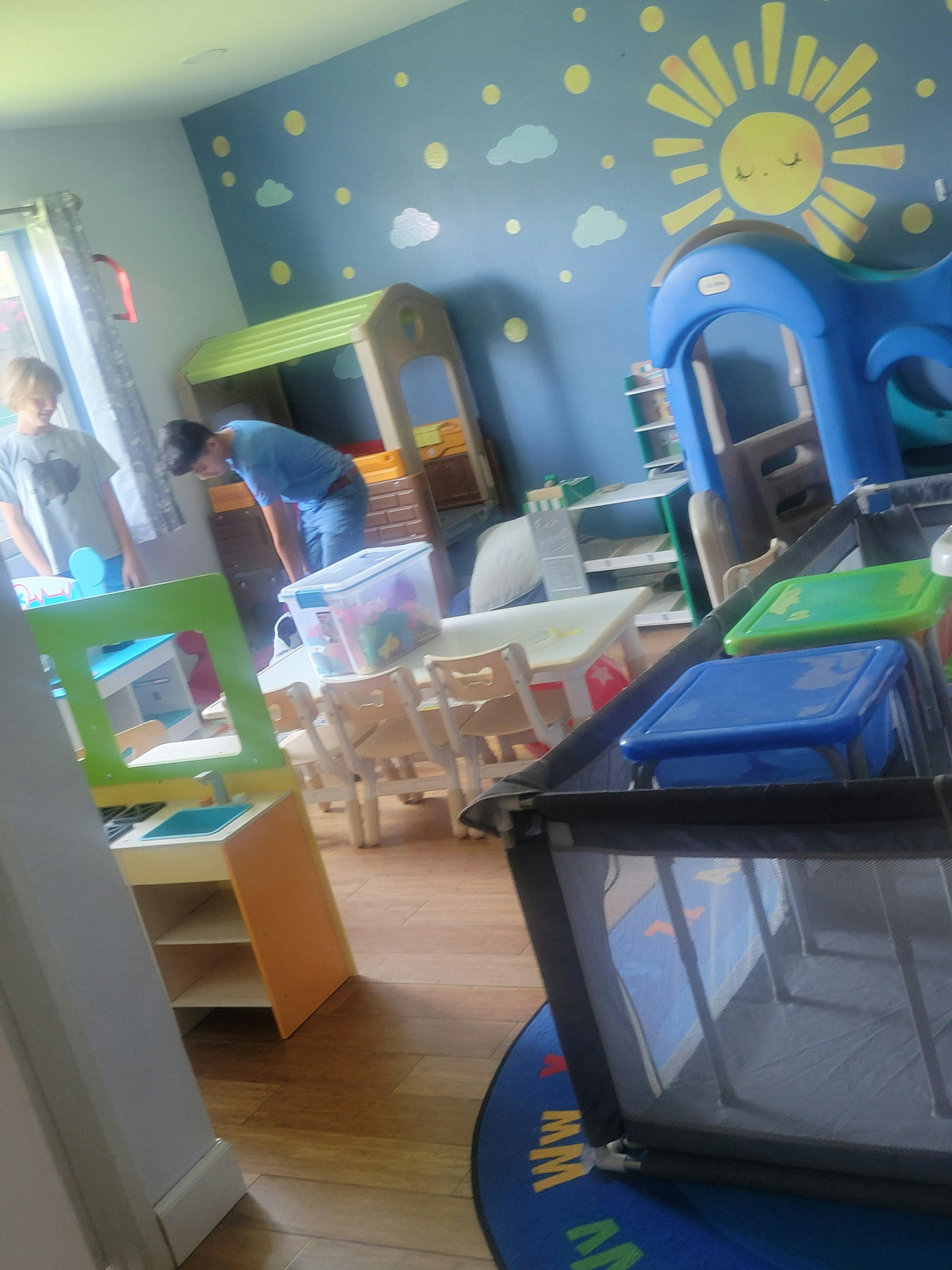 Two people in a playroom with toys and small tables