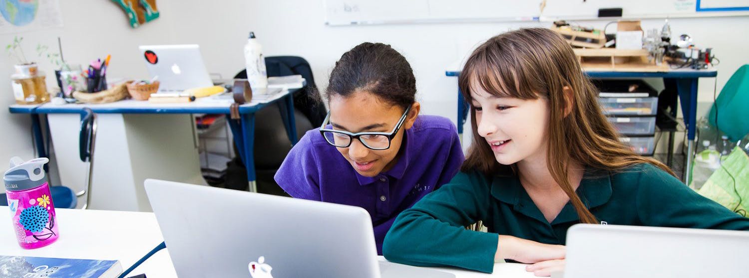 Two children looking at a laptop in a classroom