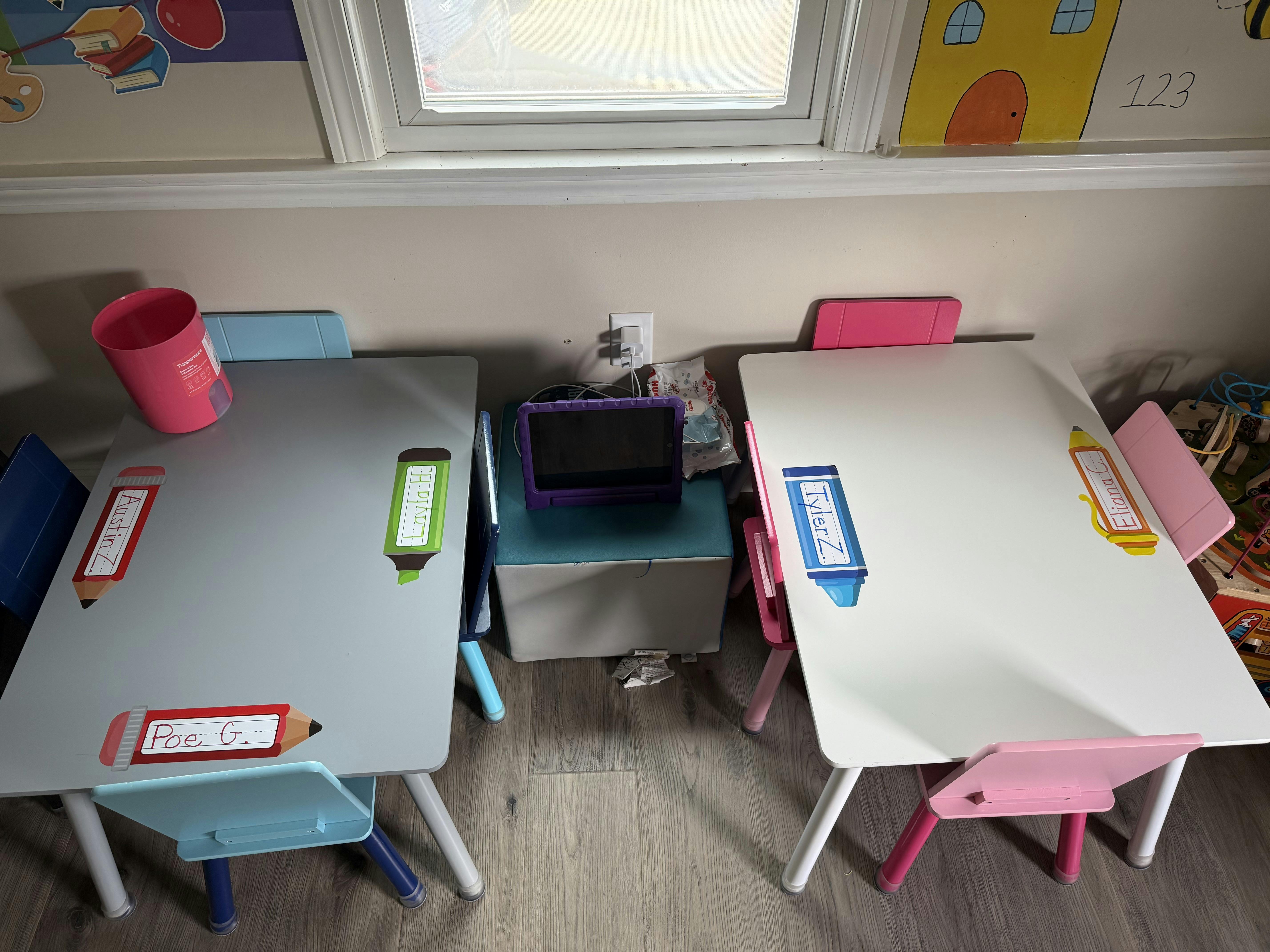 Two small tables with chairs, one gray and one white, with a tablet in between