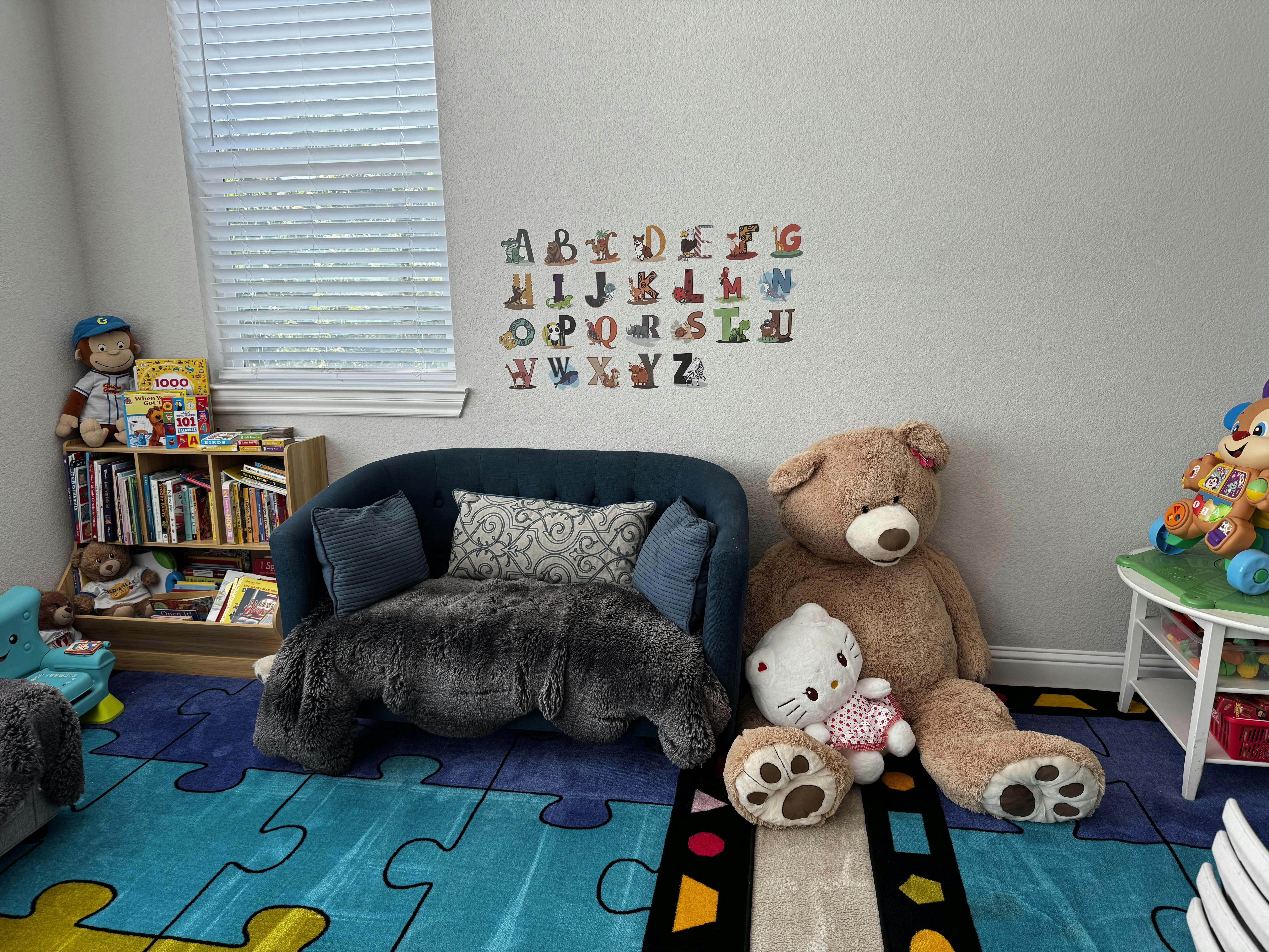 Children's playroom with a small couch, bookshelf, and stuffed animals