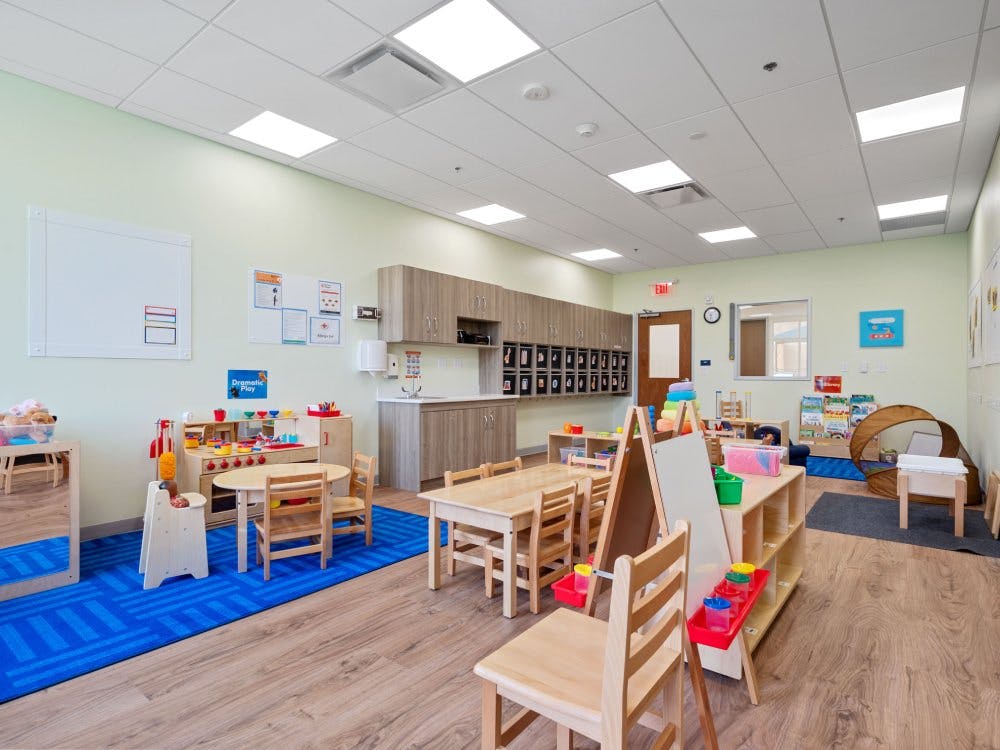 Classroom with play kitchen, small tables and chairs, and storage