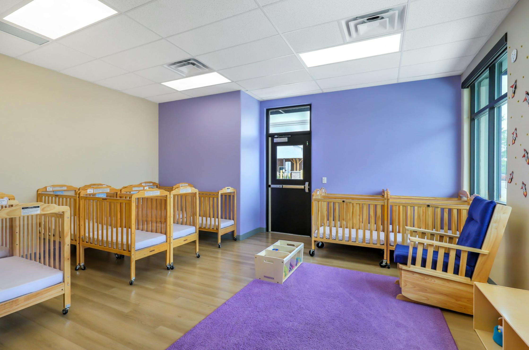 Empty cribs in a room with purple and beige walls