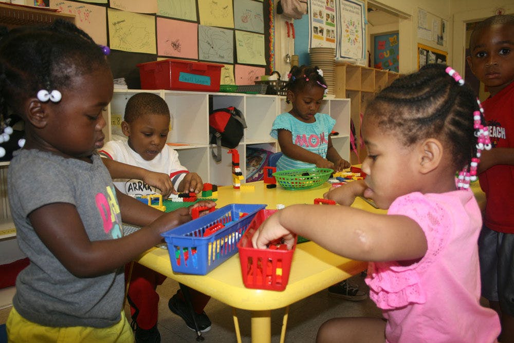 Children playing with building blocks at a table in a classroom