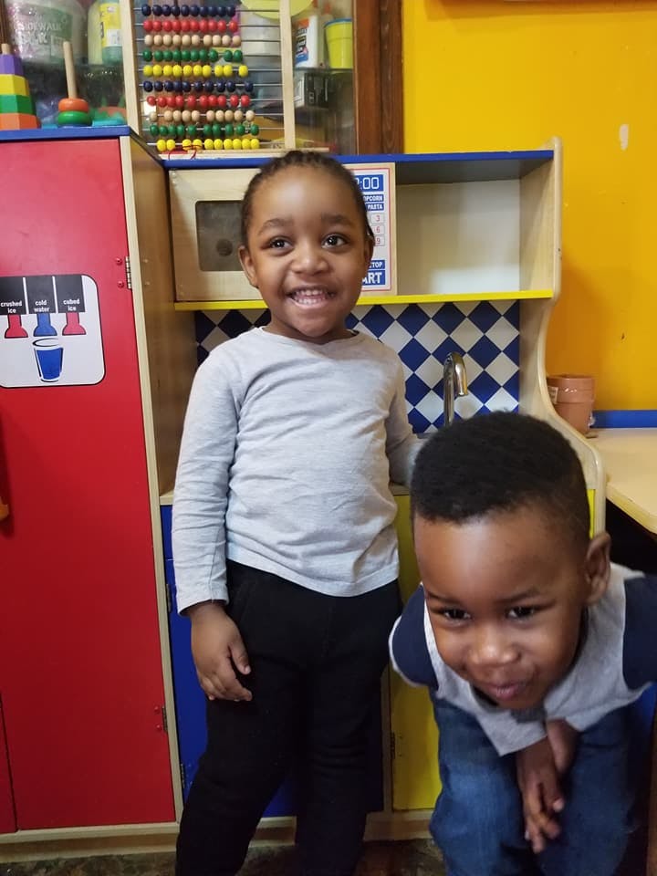 Two children in a play kitchen