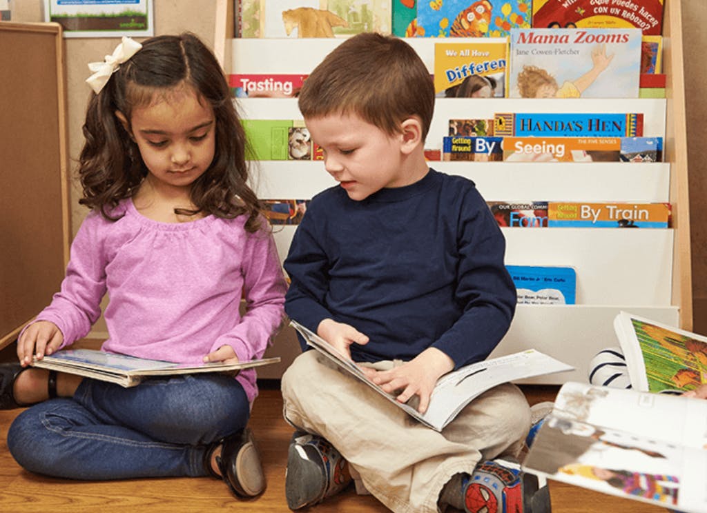 Two children sitting on the floor reading books