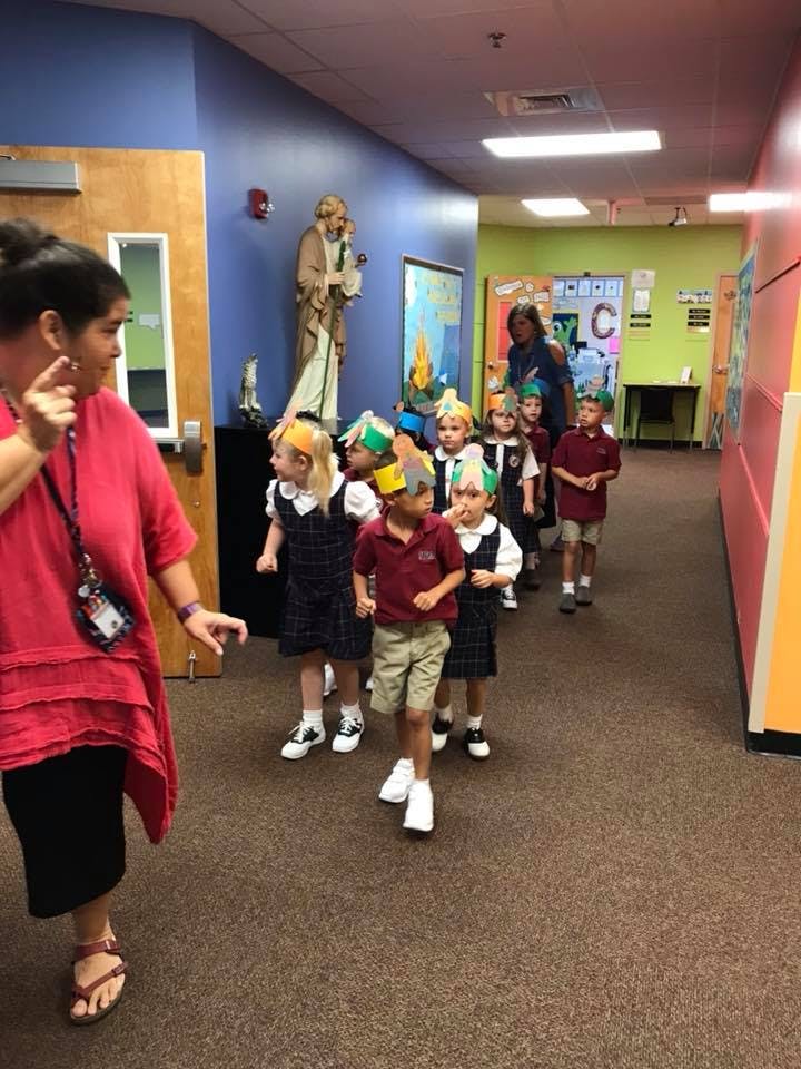 Adult and children walking in a line down a hallway