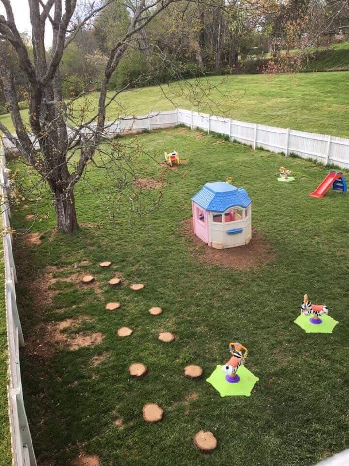 Backyard with a playhouse, slide, and tree stump path