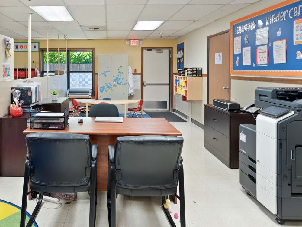 An office area with a desk and chairs, a large copier, and a bulletin board