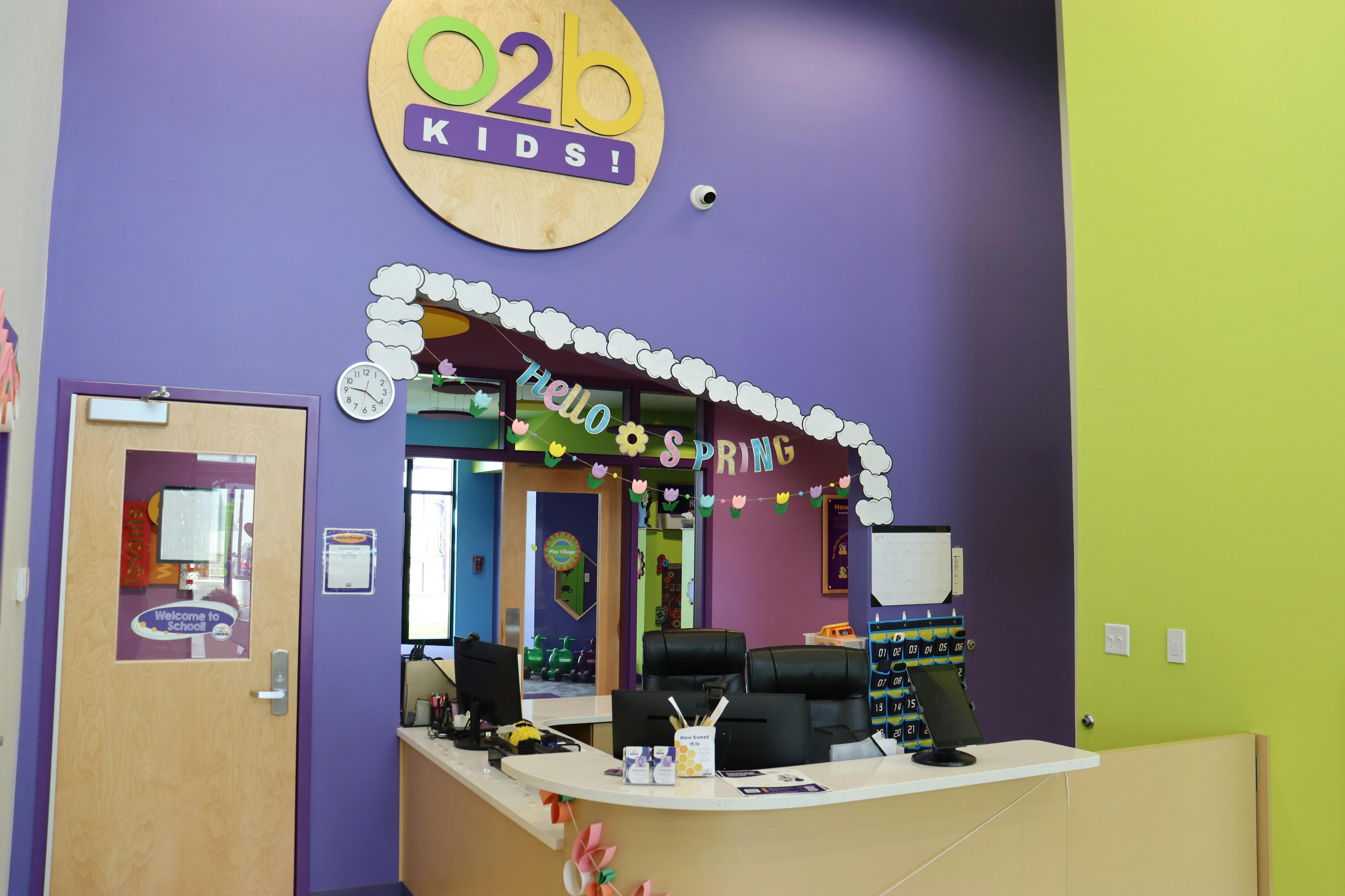 Reception desk of O2b Kids with a sign that reads, "Hello Spring"