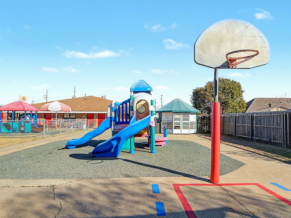Colorful playground structure with slides next to a basketball hoop